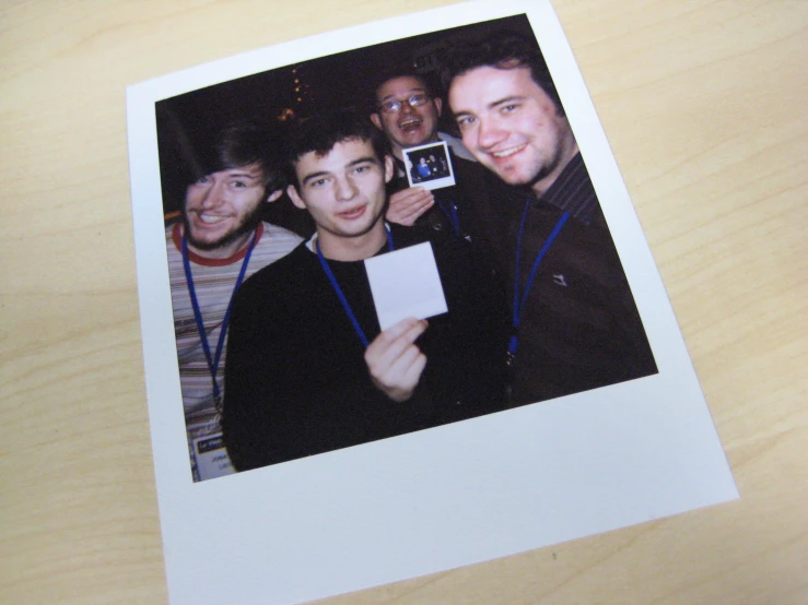 polaroid with a picture of four men standing around