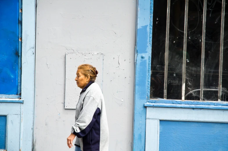 a woman walking past a closed window with a white brick