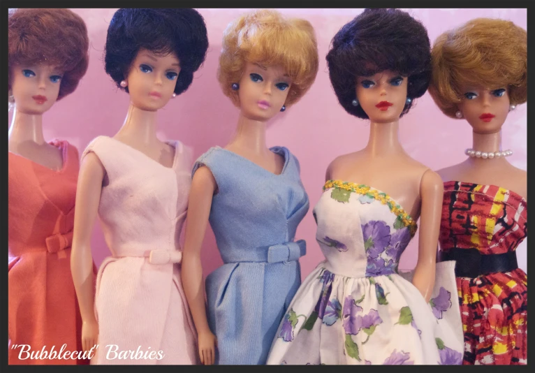 five dolls standing in a row wearing dresses