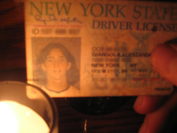 a close up of a person holding a fake new york state driver license