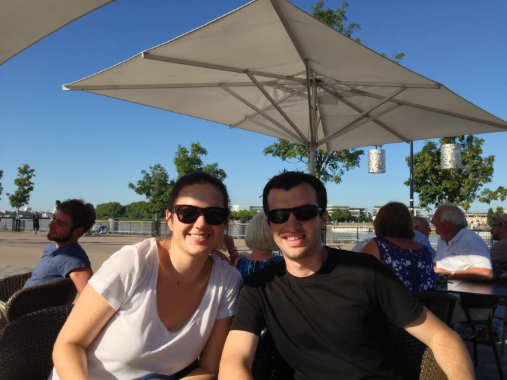 man and woman sit under an umbrella smiling