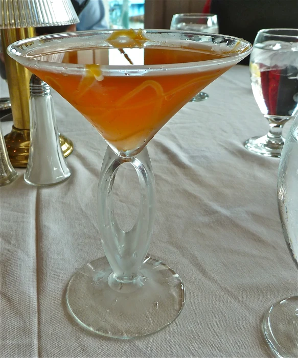 a martini sitting on a table with glasses on top of it