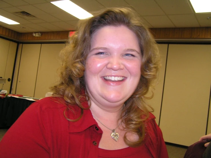 a woman smiles while standing next to a wall