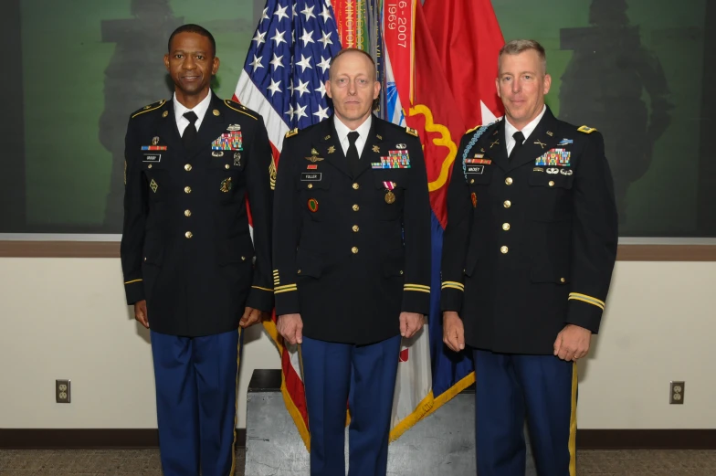 four uniformed men standing together in front of two flags