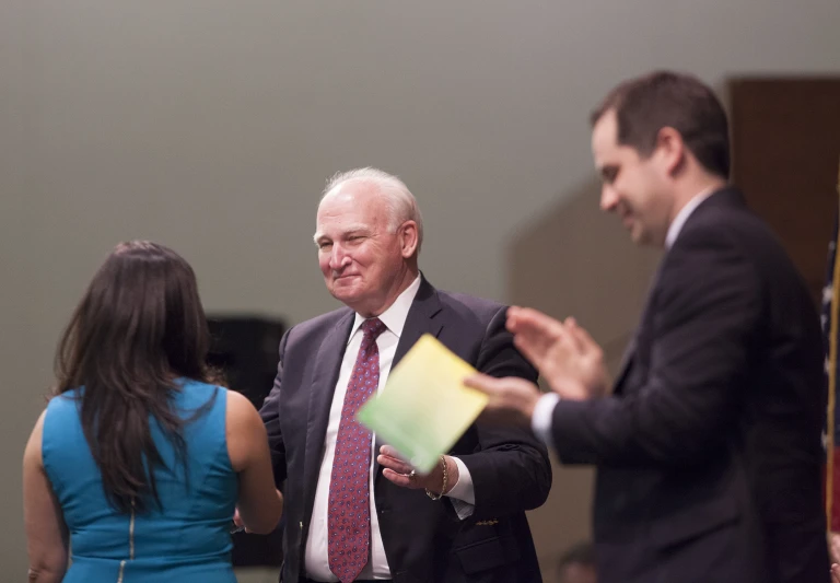 two business men speak with one holding folder