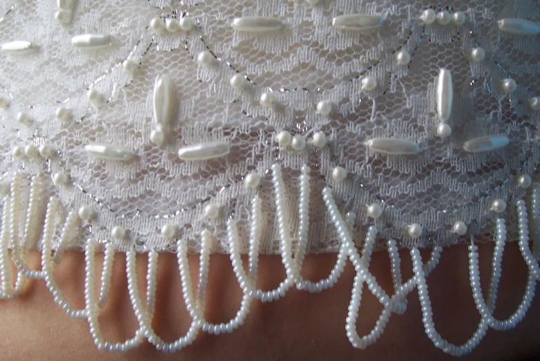 the neckline of a lace wedding garter showing pearls and beads
