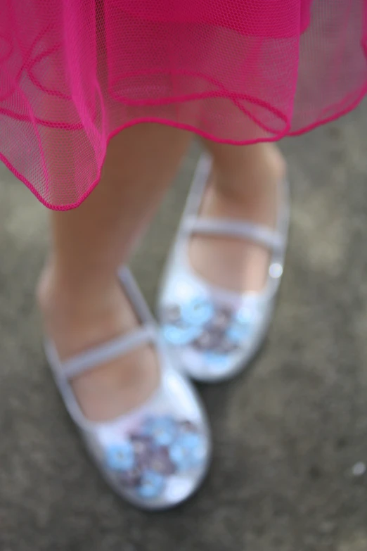 a little girl in pink and white shoes