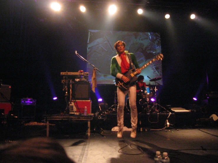 a man standing on a stage while holding a guitar