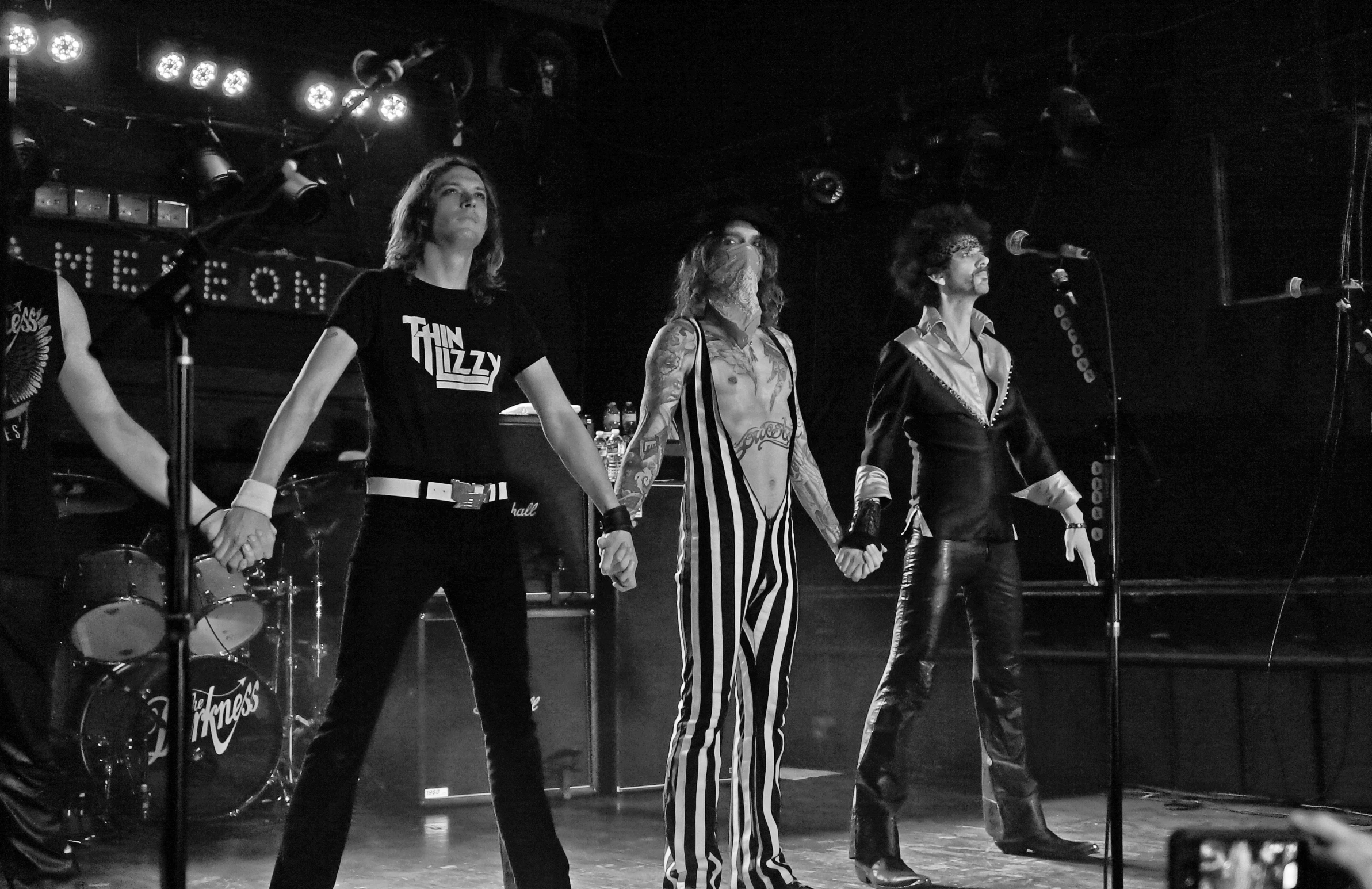 group of musicians at concert on stage with arms outstretched in front of them