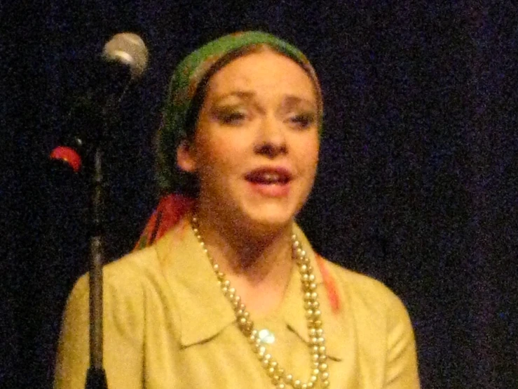 a woman in a gold shirt and a microphone