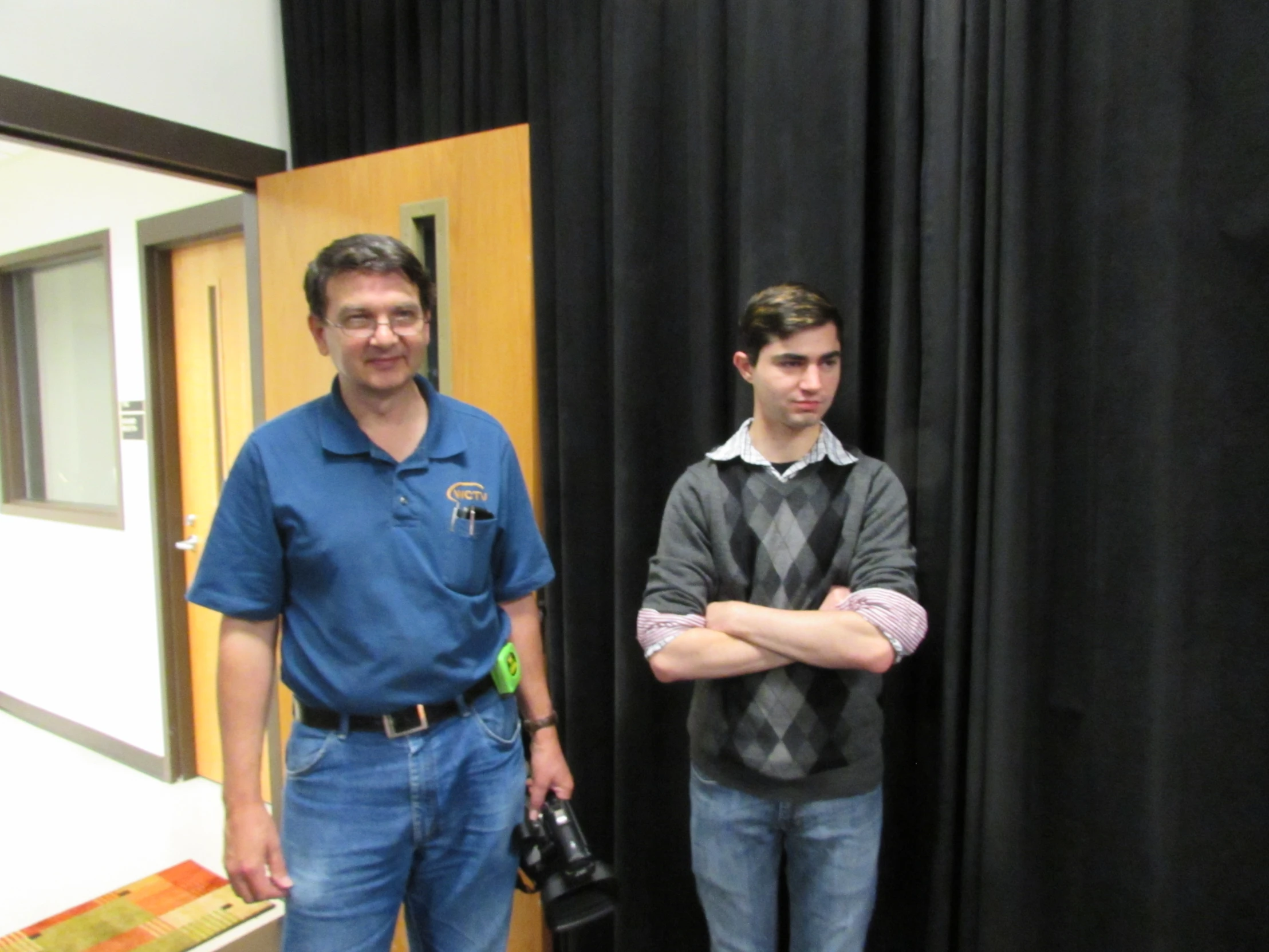 two men standing next to each other with their arms folded