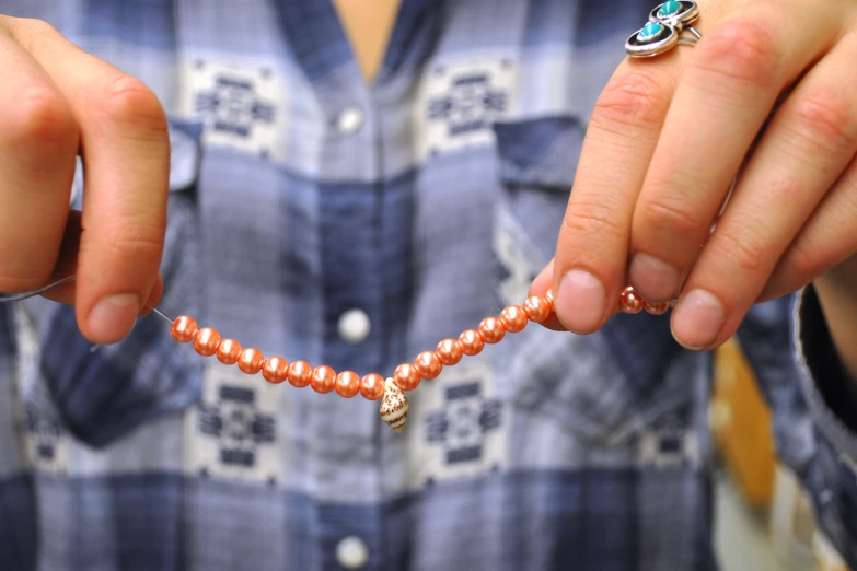 a person holding a bead necklace with an elephant design on it