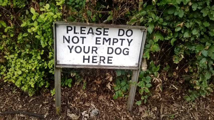 a sign is standing next to some bushes