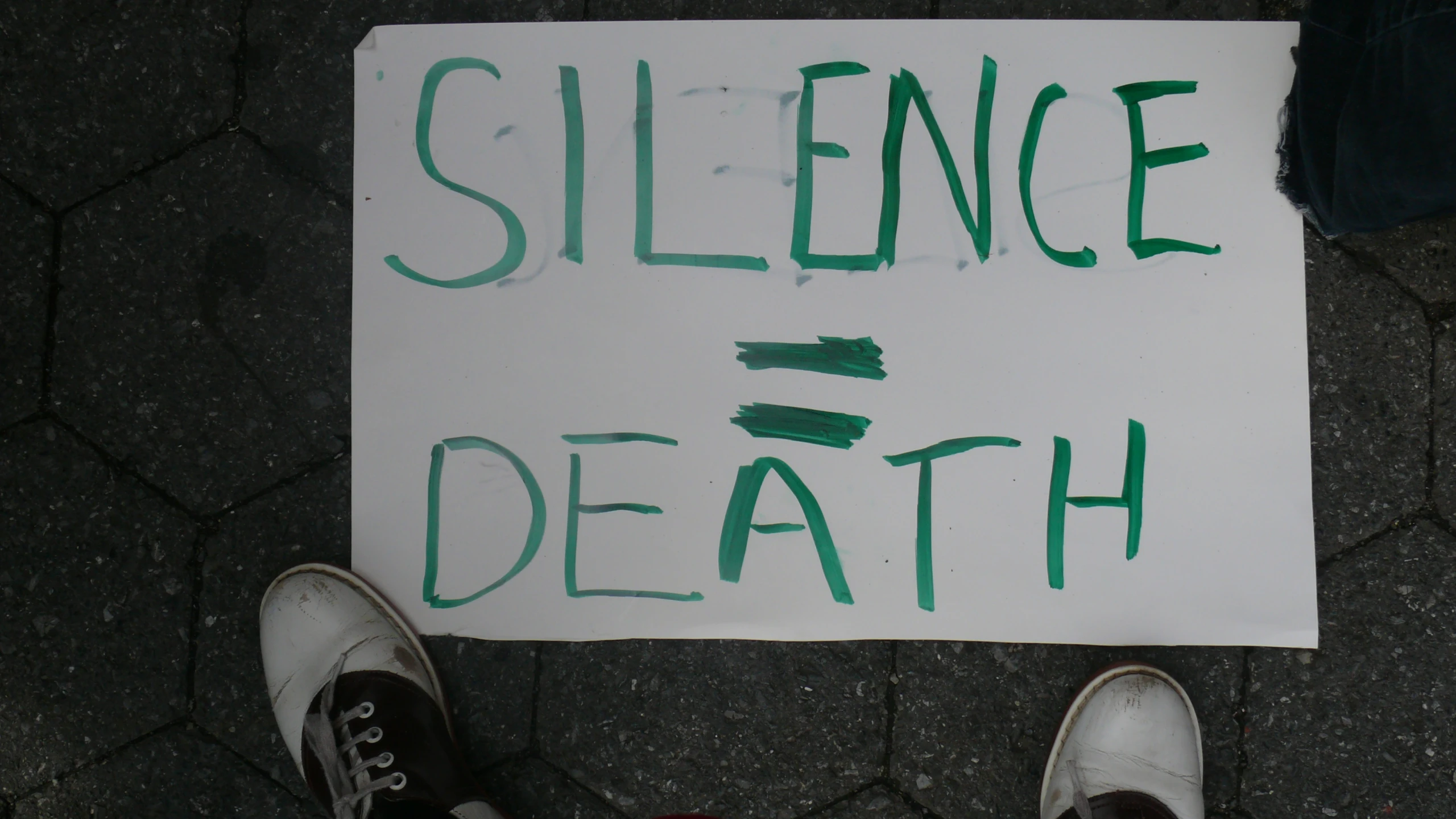 a white sheet with green writing laying on top of cement