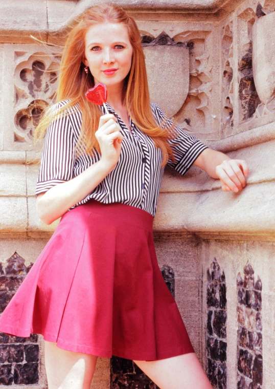 a woman with a lollipop sitting by a stone pillar