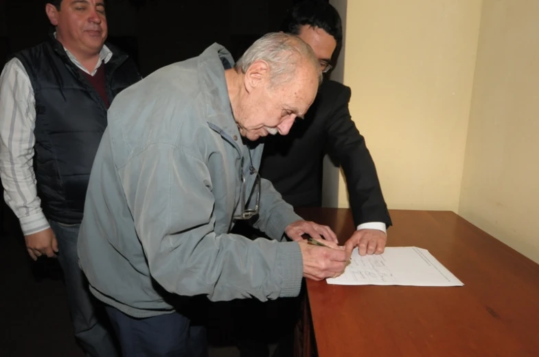 two men standing around an old man signing soing