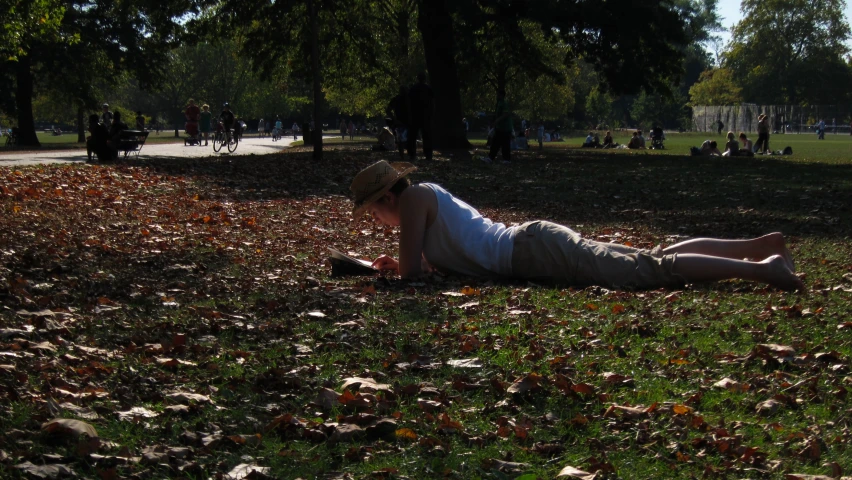 a lady laying on the grass and reading a book