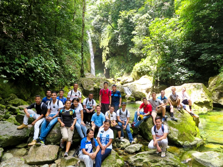 a group of young men posing in front of a waterfall