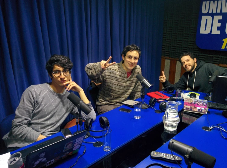 three people in front of microphones with laptops on