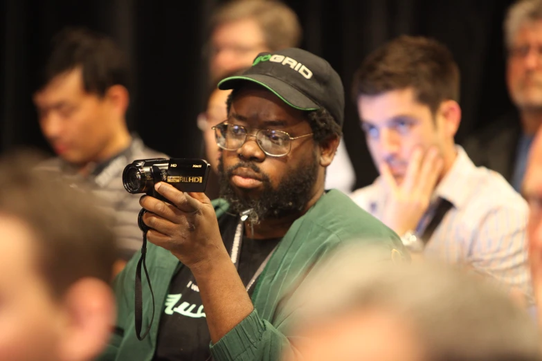 a man wearing glasses is taking a po in front of a crowd