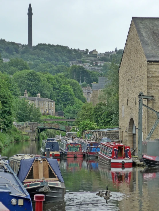 boats in water in front of stone building with hill in background