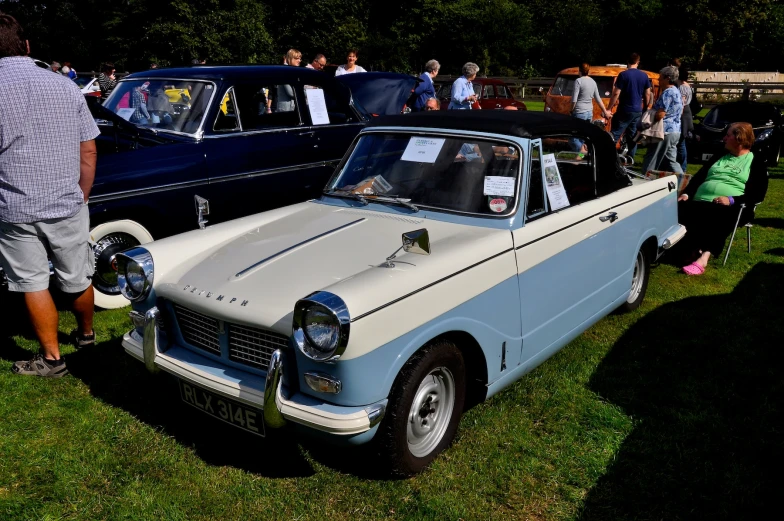 an old classic car parked in the grass