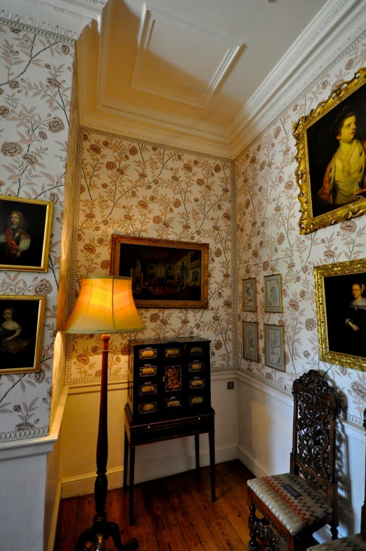 a room with pictures and a lamp with a wooden floor