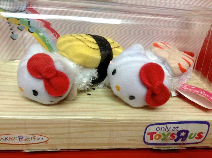 two hello kitty stuffed animals inside of a plastic box