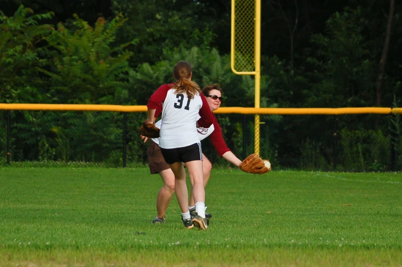 two young women are playing baseball in the field