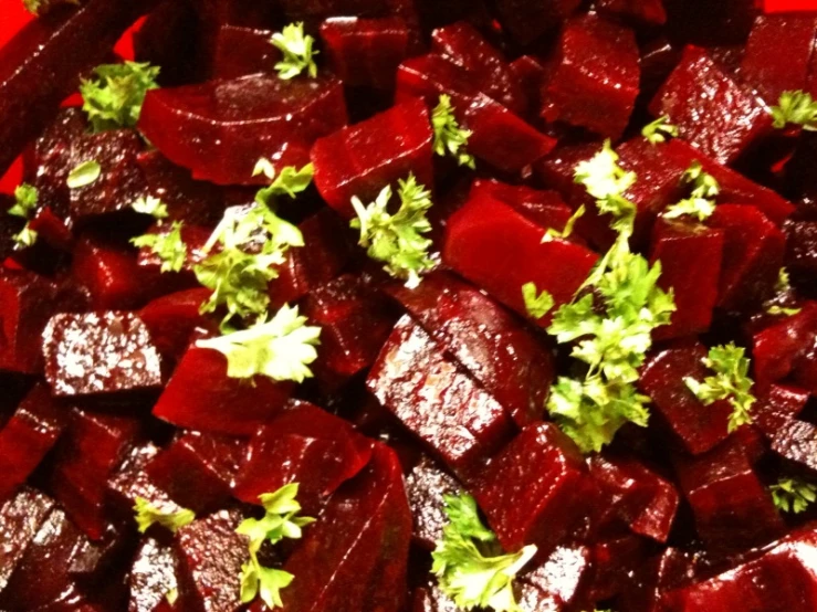 sliced beets and green leafy vegetables sitting on a red plate