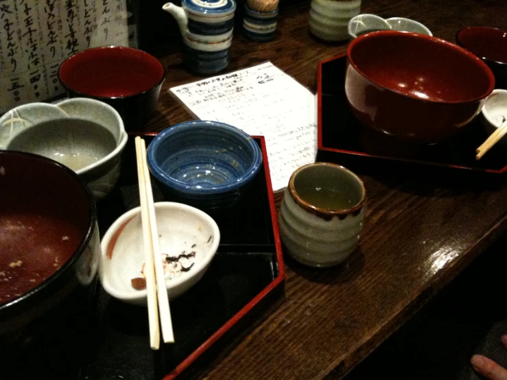 asian - style bowls, rice sticks, and chopsticks sit atop a table