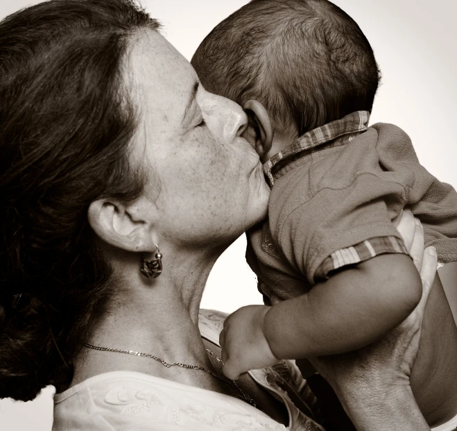 a woman and a baby that are kissing