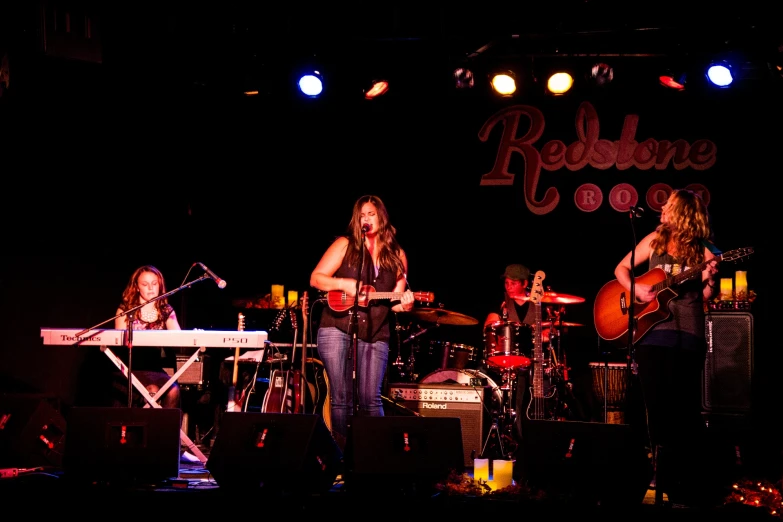 a band with three people playing guitar in front of a microphone