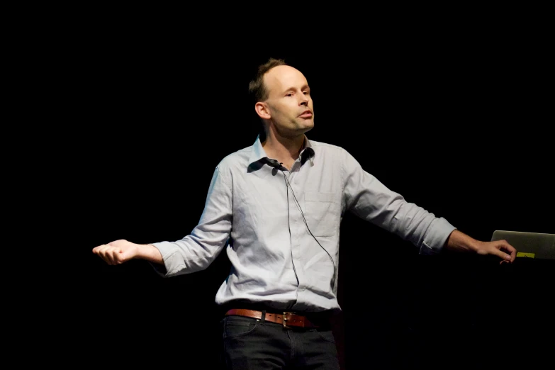 a man in white shirt and black pants in front of a black background