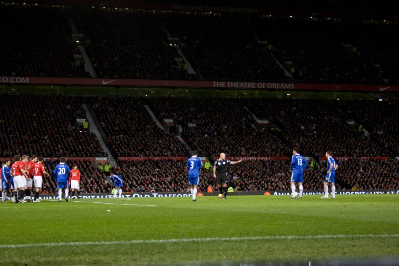 a referee watches as players observe from the sideline