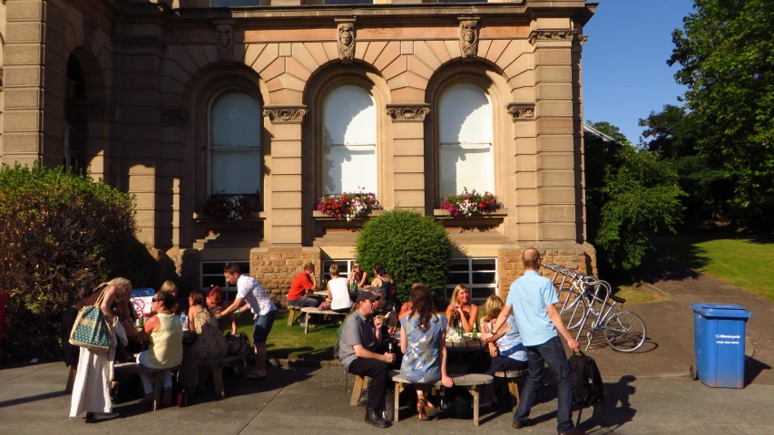 a bunch of people are gathered around a table outside