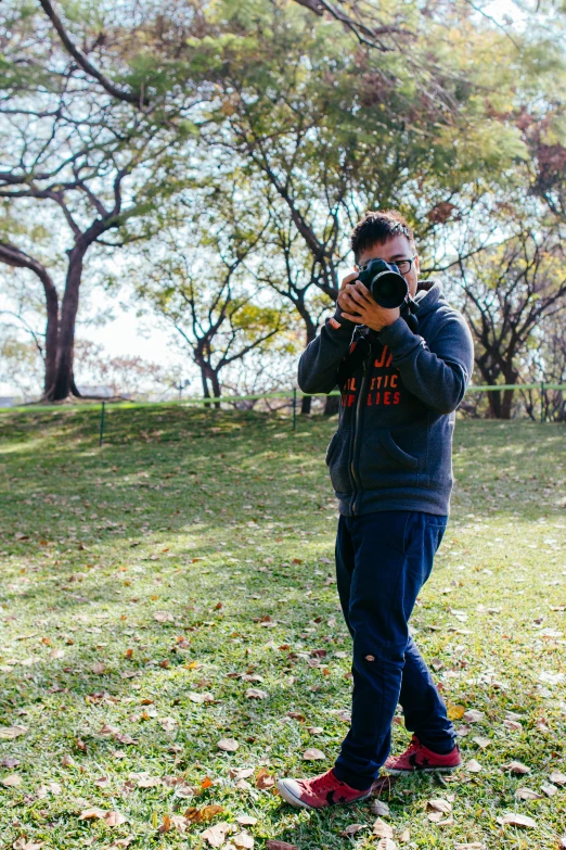 a man taking a picture with a camera in a park