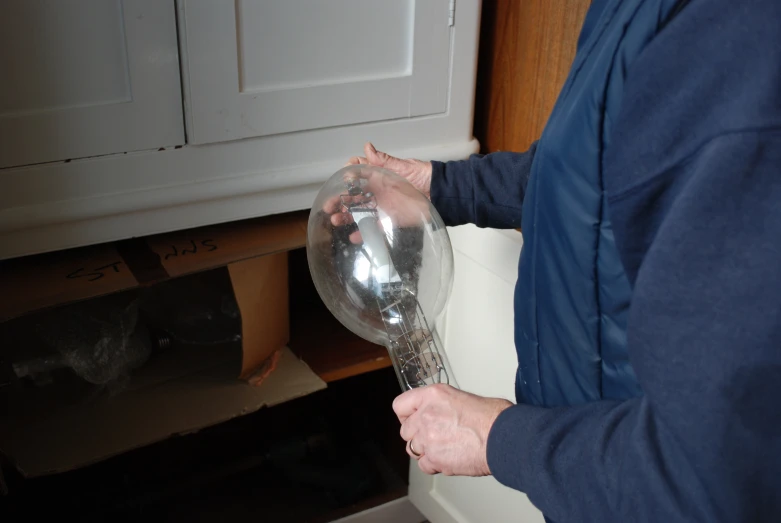 a person holds a large clear balloon near a shelf