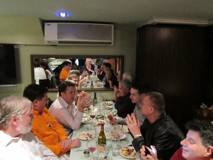 a large group of people sit at a table with food and drinks