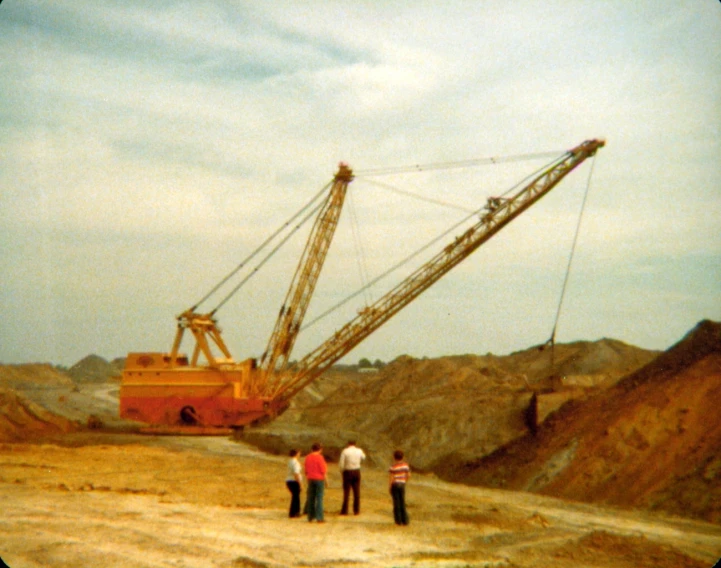 three people are standing in front of the huge crane