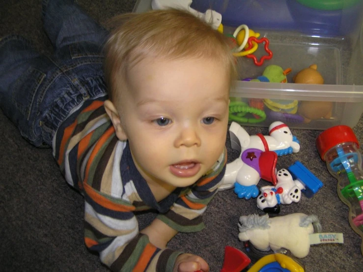 a baby laying on the floor with toys
