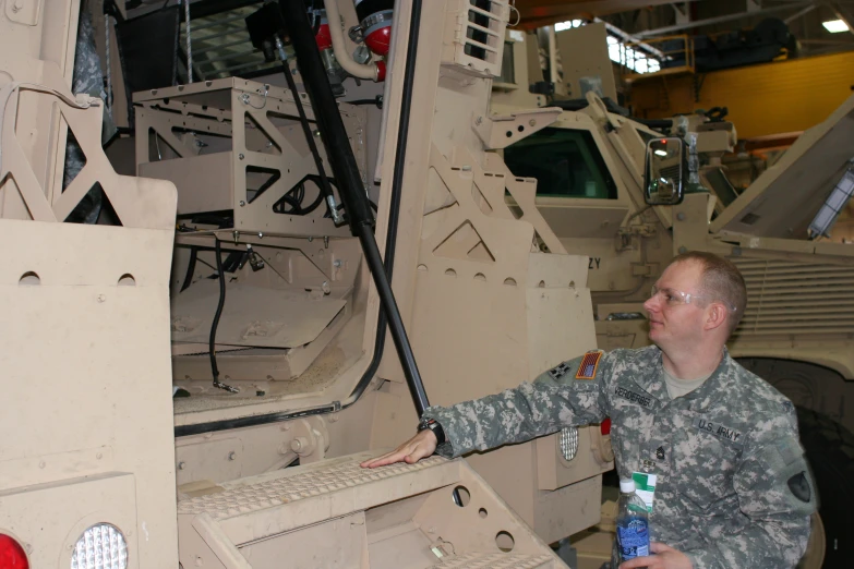 a man in camouflage stands next to a vehicle