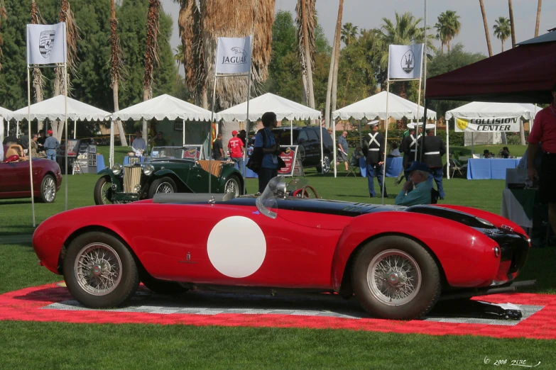 a man sitting in a red sports car at an outdoor event