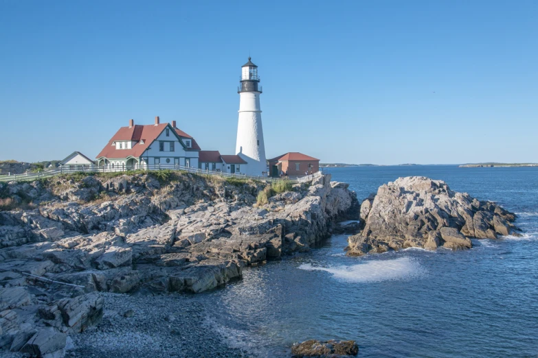 a lighthouse stands on top of an rocky outcropping