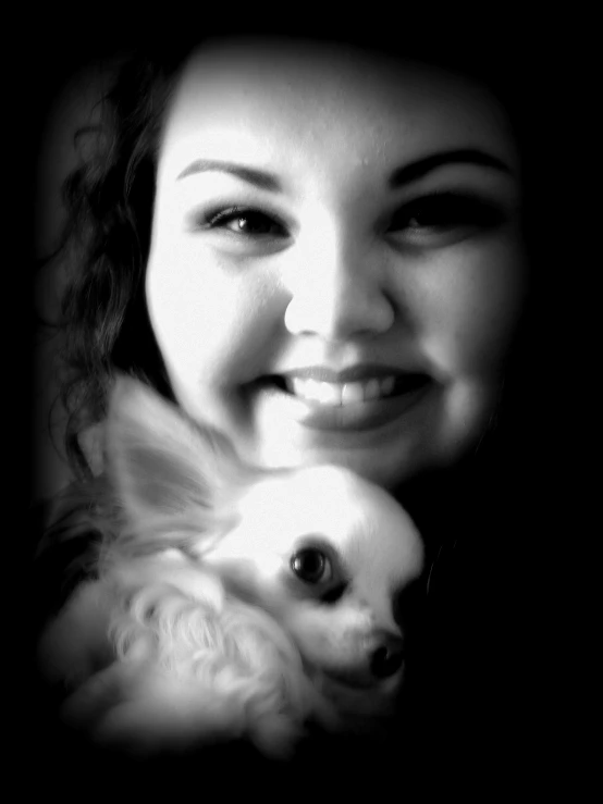 a young woman smiles and hugs her dog