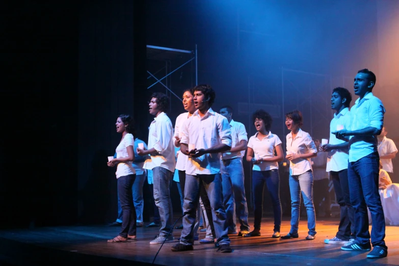 group of young men singing on stage, with hands in pockets