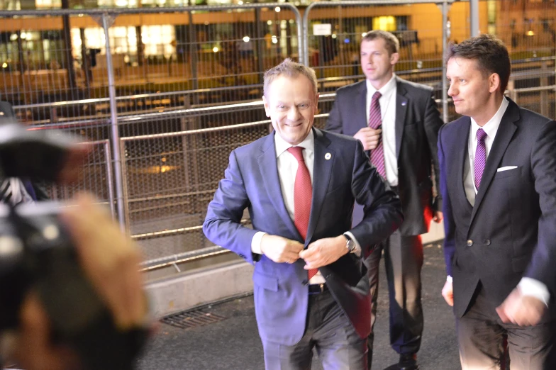 three men in business attire with cameras taking pictures