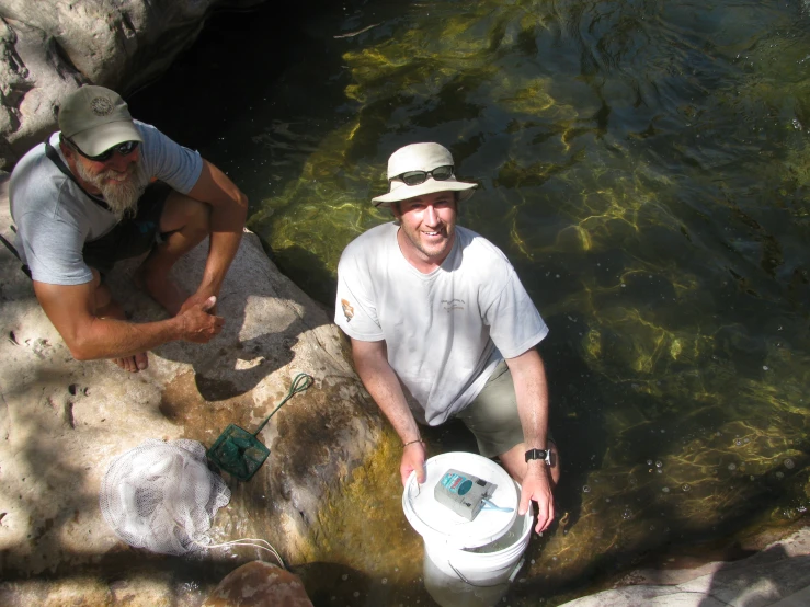 two men in white hats next to a pool