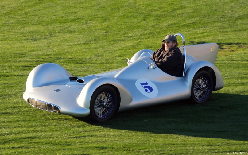 a man sits in a very expensive car on the grass