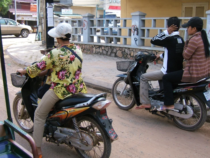 a group of three people riding motorcycles down a street